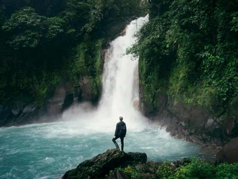 Traveler standing before a tropical waterfall in Costa Rica – La Fortuna area